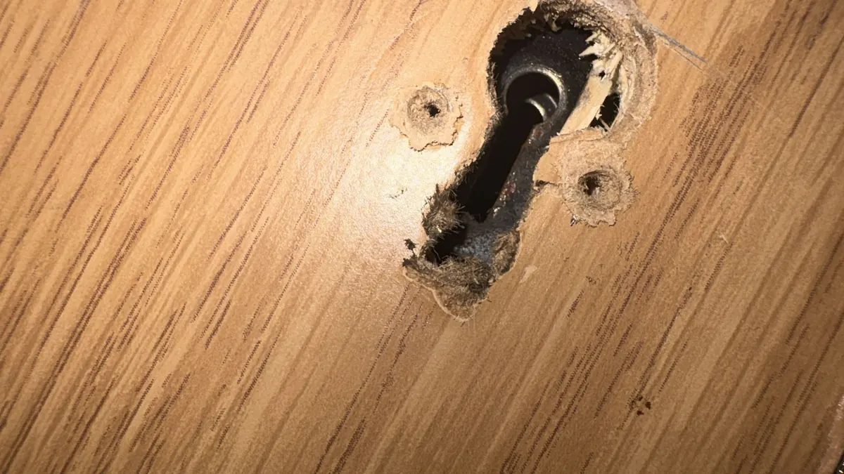 Holes drilled around a keyhole in a laminate door.