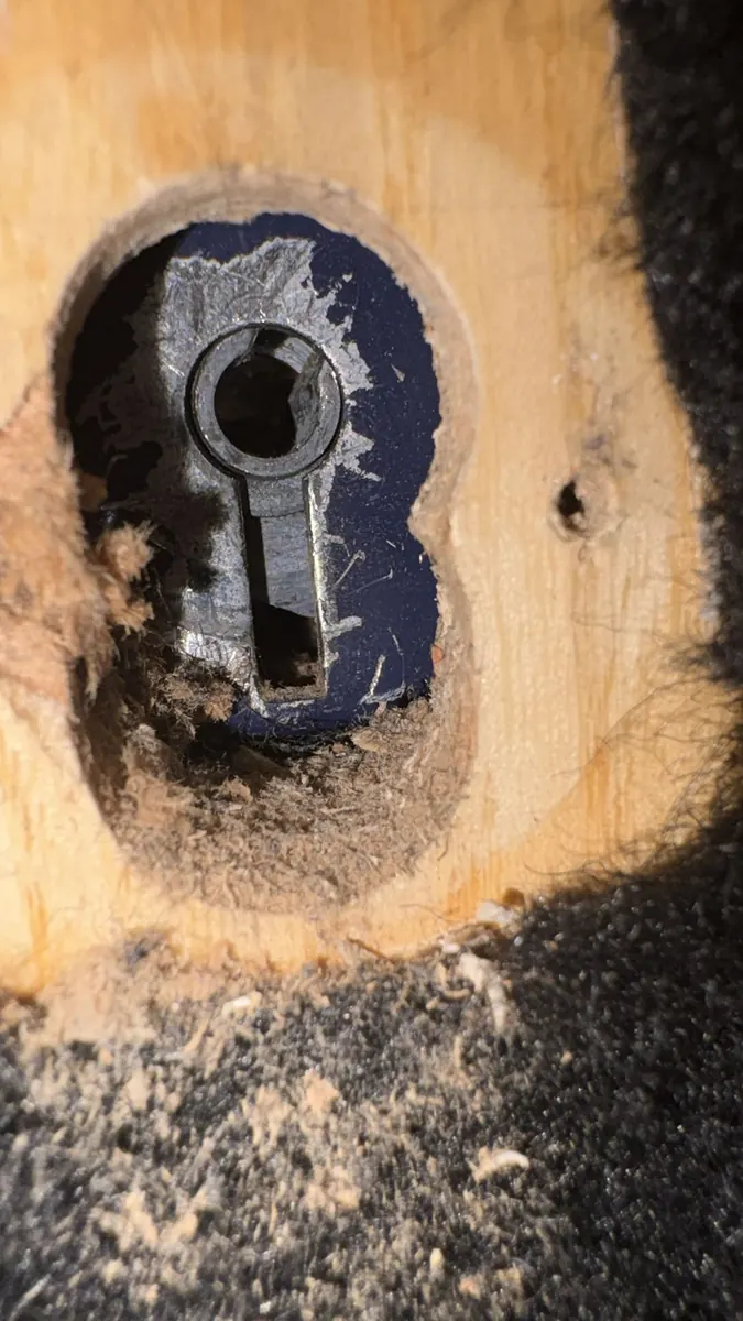 A mortice lock pocket gouged out, with the timber splintered around the keyhole.