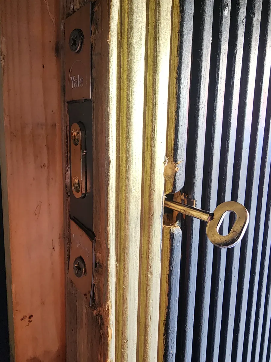 A nightlatch key in an older wooden commercial door.
