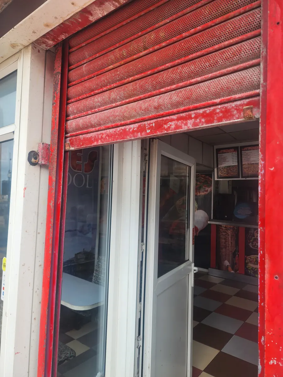 A shop entrance with a roller shutter and glazed door.
